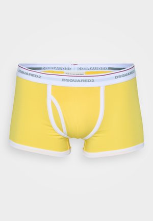 Gula boxershorts med en tight passform, vit kant, och en midjeresår med märket "DSQUARED2" i grå text.