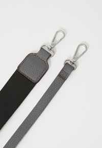 Grå læderrem med en struktureret overflade, der har metalclips. Den ene ende har en sort elastisk sektion. Enkel design, funktionelt hardware.