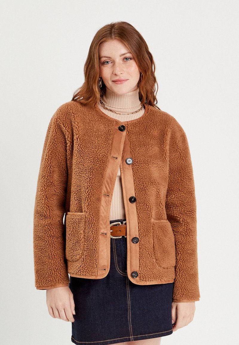 Veste en polaire marron avec une texture douce, encolure ronde, devant à boutons, deux poches avant et des accents beiges sur les bords.