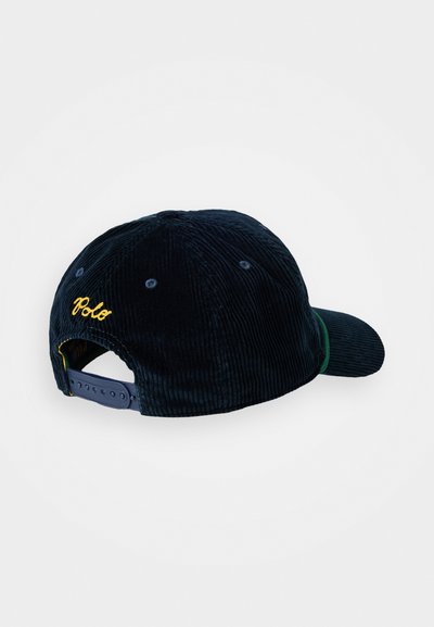 Casquette de baseball en velours côtelé bleu marine avec une visière courbée, un accent vert et une broderie jaune "Polo" à l'arrière. Fermeture à pression ajustable.