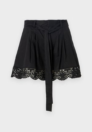 Black skirt with a textured lace hem featuring scalloped edges and pompom details. The design includes a tied waist accent.