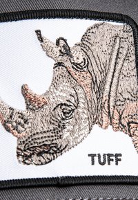 Parche bordado con un rinoceronte en tonos beige y gris, sobre un fondo blanco con borde negro y el texto "TUFF" debajo.