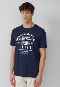 Navyblauwe katoenen t-shirt met witte tekstprint. Ronde hals en korte mouwen. De tekst bevat "Beachcraft L.A." en "Venice Beach."