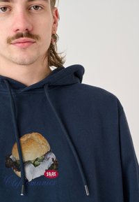 Navy blue hoodie featuring a graphic of a sandwich with lettuce, displayed on the front; includes red price tag label reading "19,91."