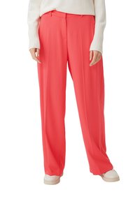 Coral wide-leg trousers made of smooth fabric; features pleats, a high waist, and belt loops; styled with white sneakers and a light sweater.