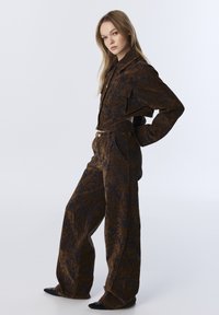 Brown and navy patterned outfit made of soft fabric, featuring a collared jacket and loose, wide-leg pants with side pockets and a button closure.