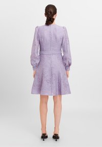 Lilac dress with puff sleeves, textured fabric, fitted waist, and flared skirt. Features a back zipper and button accents on sleeves.
