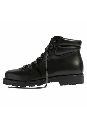 Bota de senderismo de cuero negro con un cuello acolchado, cordones grises, ojales metálicos y una suela de goma resistente con surcos profundos para tracción.