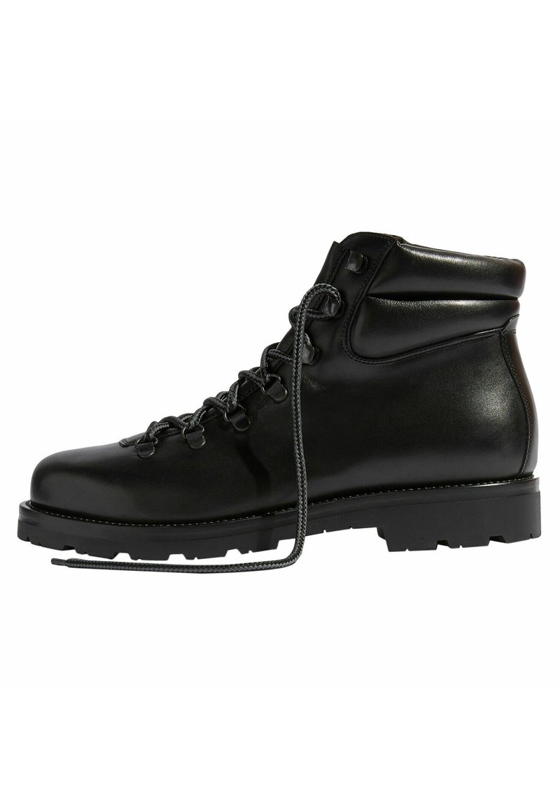 Bota de senderismo de cuero negro con un cuello acolchado, cordones grises, ojales metálicos y una suela de goma resistente con surcos profundos para tracción.