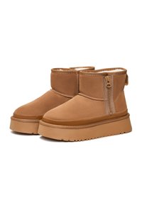 Beige Wildleder-Ankle Boots mit weicher Innensch lining, seitlichem Reißverschluss, erhöhtem Plateausohle und runder Zehenform. Strukturiert Oberfläche und genähte Akzente.