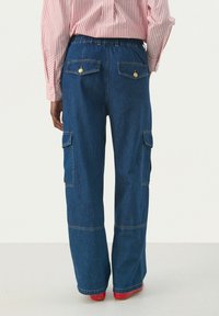 Pantalones cargo de mezclilla en azul oscuro con cintura elástica. Presenta dos bolsillos laterales y dos bolsillos traseros con botones en tono dorado.