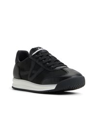 Sneakers in pelle nera con finitura testurizzata, dotate di una suola bianca, lacci neri e sottili accenti di design sulla parte superiore.