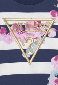 T-shirt in cotone a righe navy e bianche con un design floreale, logo ricamato dorato a forma triangolare e accenti di rosa e verde.