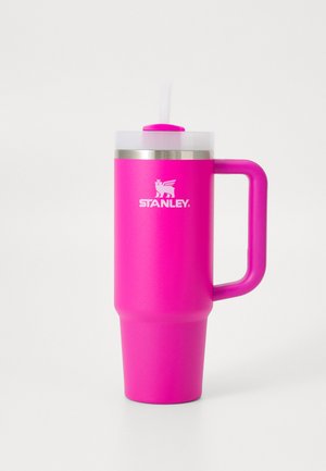 Tall pink insulated travel mug with handle, clear lid, white straw, and Stanley logo on front against plain background.