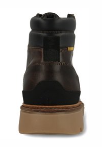 Bruine leren enkellaars met zwarte accenten, rubberen zool, gevoerde kraag en een elastisch paneel aan de achterkant voor eenvoudig dragen. Subtiele stiksel details.