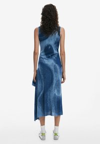 Blue, sleeveless dress featuring a fluid design with varying dark and light patterns, knee-length, made from a smooth fabric.