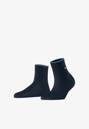 Paar marineblaue, gerippte Knöchelsocken mit einem kleinen runden silbernen Logo an der Außenseite jeder Socke.