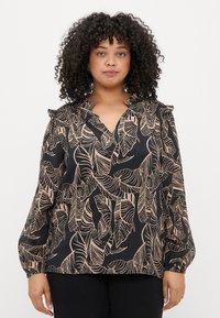 Blusa preta com padrão de folhas em bege, apresentando um decote em V e detalhes de babados nos ombros. Mangas longas, franzidas, com punhos.