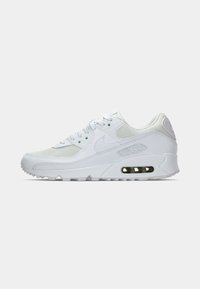 White Nike sneakers with mesh and leather materials, rounded toe, lace-up front, and visible air cushioning in the heel. Textured accents.