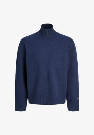 Pull en col roulé bleu marine en tissu doux, avec des bords ribbés aux manches et au bas, et un logo discret sur la manche.