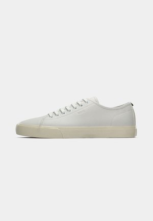 Lys grå sneakers med overdel i canvas, rund tå, gummisåle og flate snøringer. Minimalistisk design med subtil merkevare på siden.