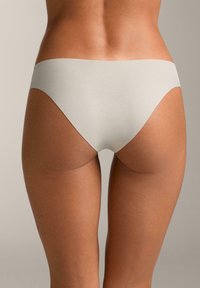 Lenjerie de bikini bej, realizată dintr-un material neted și elastic. Deschideri înalte pentru picioare și acoperire minimă, cu un design fără cusături pentru confort.