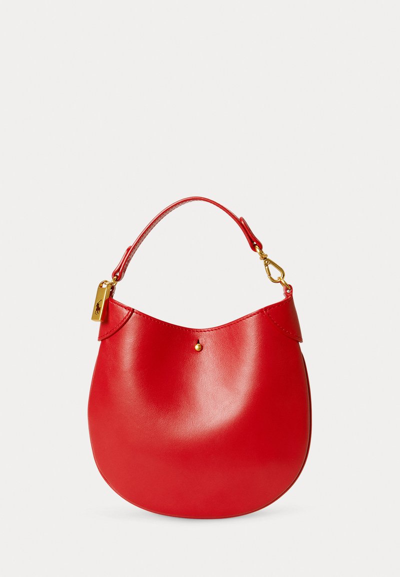 Κόκκινη δερμάτινη τσάντα με καμπύλη σχήματος, κοντή λαβή και χρυσές λεπτομέρειες. Λείος υφασμάτινος χαρακτήρας με μια μικρή κυκλική διακόσμηση μπροστά.