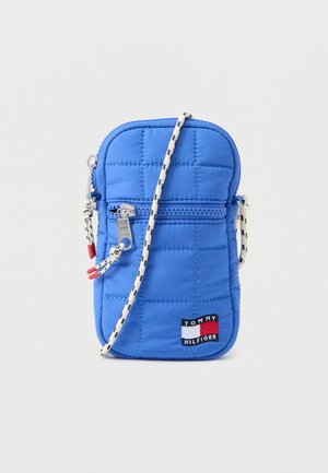 Blue quilted crossbody pouch with front zipper pocket and white-black patterned strap, featuring a Tommy Hilfiger logo patch.