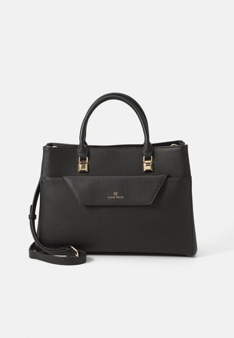 Black textured leather handbag with top handles, front flap pocket, gold hardware, and detachable shoulder strap on white background.