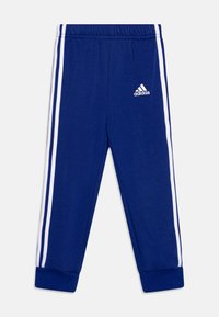 Blaue Baumwoll-Sweatpants mit weißen Seitenstreifen, elastischem Taillenbund und gerippten Bündchen. Mit einem weißen Adidas-Logo auf dem linken Oberschenkel.