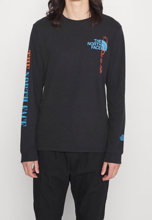 Camisa de manga larga negra con gráficos en azul y naranja, que presenta el texto "THE NORTH FACE" en el frente y la manga. Material de algodón suave.