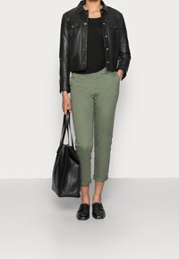 Giacca di pelle nera, canotta nera, pantaloni cropped verde oliva, scarpe slip-on nere e una borsa a tracolla nera. Design semplice e moderno.