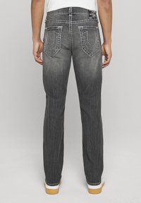 Zwarte spijkerbroek met een rechte pijp, voorzien van contrasterende stiksels op de achterzakken en een versleten textuur.