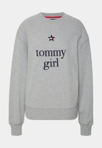 Felpa grigia con polsini e orlo a costine, caratterizzata dalla scritta "tommy girl" ricamata in blu navy, con una stella come accento e colletto rosso.