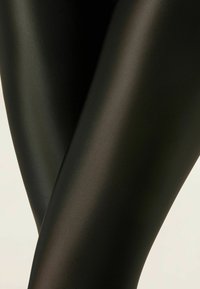 Bløde, sorte leggings lavet af glat, strækbart materiale. Har et slankt, tætsiddende design med en mat finish.