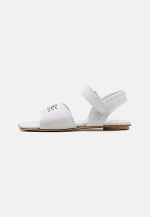 Witte platte sandalen met een open teendesign, elastische enkelband en bovenwerk van gladde stof. Voorzien van een houten zool en subtiele stiksels.