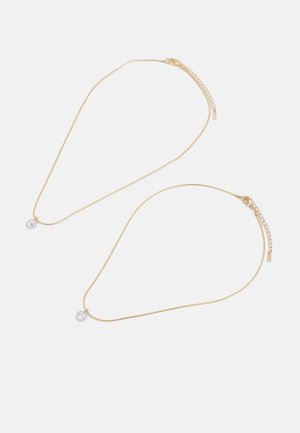 Collier en ton or doté d'un design de chaîne délicate avec un pendentif en cristal transparent. Longueur ajustable avec un fermoir et une chaîne d'extension.