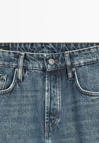 Blauwe spijkerbroek van denim met een metalen knoop, riemlussen, voorzakken en zichtbare stiksels bij de tailleband en het gulpgebied.