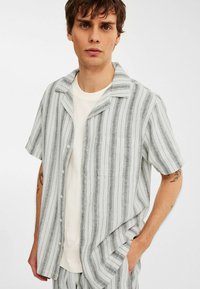 Korte mouwen knoopshirt in lichtgrijs met donkere verticale strepen, voorzien van een zak, gekraagd ontwerp en een ontspannen pasvorm. Zachte textuur.