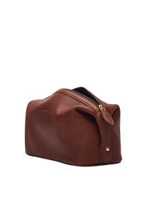 Brown leather toiletry bag with a smooth texture, rounded shape, and a gold zipper. Features a small leather tag and minimal branding.