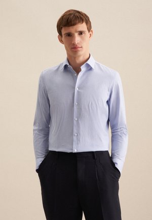 Hellblau gemustertes Hemd mit Button-Down-Kragen, langen Ärmeln und tailliertem Design, kombiniert mit dunklen Hosen.