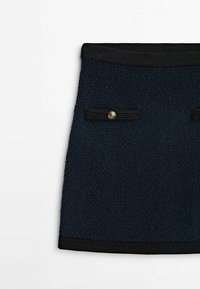 Jupe texturée bleu marine foncé avec bordure noire, deux poches avant boutonnées, présentée à plat sur fond blanc.