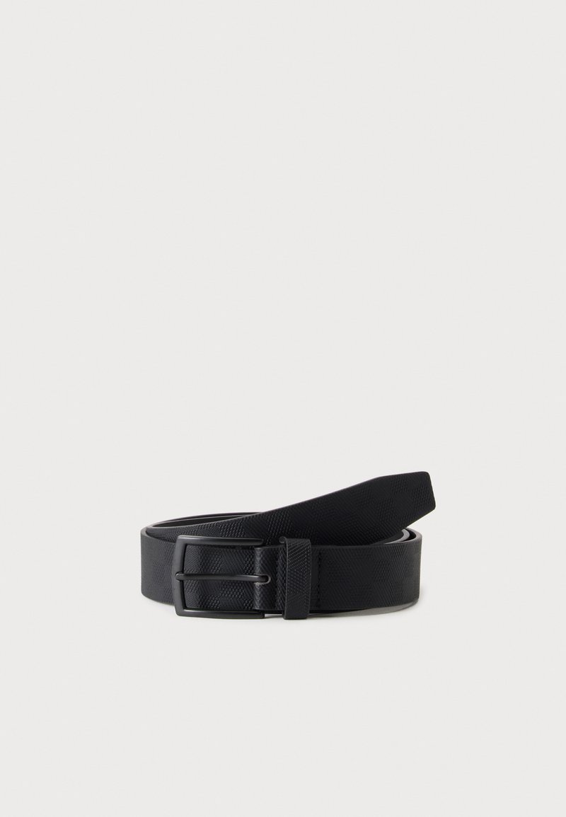 Ceinture en cuir noir texturé, roulée avec une boucle métallique rectangulaire et une boucle de ceinture sur fond clair.