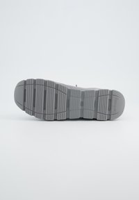 Semelle de sneaker grise avec un motif de grip texturé, présentant des stries et des rainures pour l'adhérence. Bord lisse et design de bout arrondi.