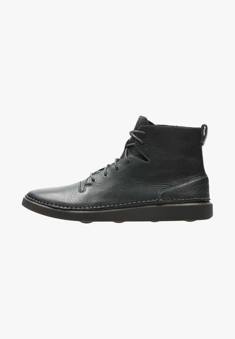 Bottine en cuir noir avec lacets latéraux, bout arrondi, semelle cousue et languette à l'arrière pour un enfilage facile.