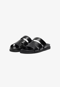 Sorte skinnesandaler med krokodillepreget tekstur, utstyrt med to brede stropper og en flat såle. Enkelt design med minimale dekorasjoner.