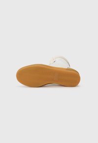 Sneaker con una toma superiore in tessuto beige, suola in gomma a effetto wood, motivo di battistrada a zigzag e cinturino regolabile. Presenta una punta arrotondata e un soletta imbottita.