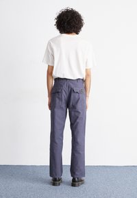 Navy blue cargo pants with two back pockets, straight legs, and a waistband. Paired with a white short-sleeve t-shirt and black shoes.