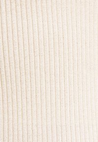Cream-colored ribbed fabric with vertical knit texture and subtle variations in thread thickness and color.