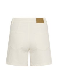 Shorts en denim blanc cassé avec deux poches arrière, passants pour ceinture et un patch de marque en cuir marron sur le côté droit de la ceinture.